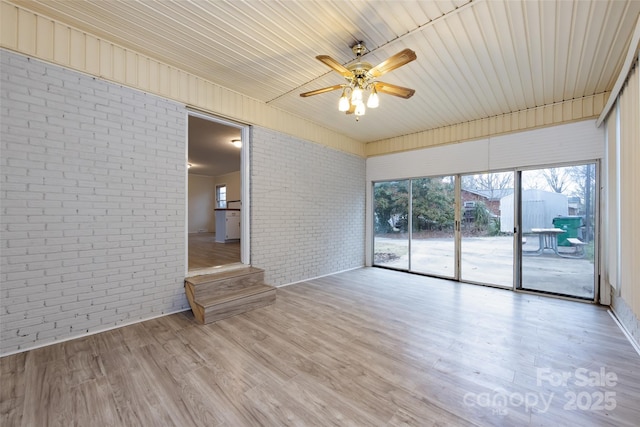 4601 Mendham Dr, Charlotte, NC 28215 - spare room featuring brick wall, ceiling fan, and wood finished floors