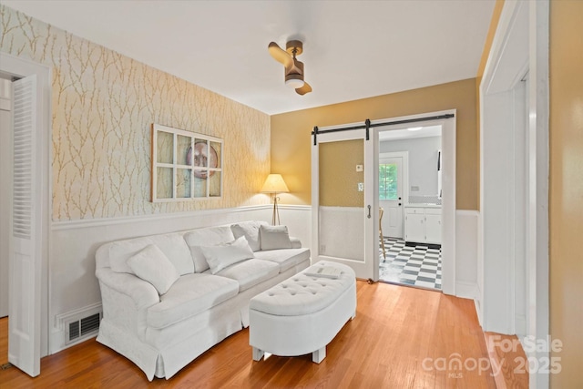 747 9th St NW, Hickory, NC 28601 - living room with a wainscoted wall, a barn door, wood finished floors, and wallpapered walls