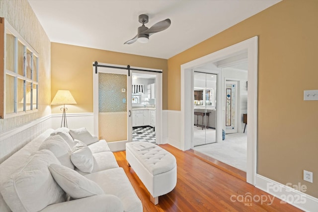 747 9th St NW, Hickory, NC 28601 - living area with a wainscoted wall, a barn door, a ceiling fan, plenty of natural light, and wood finished floors