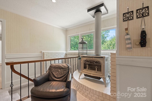 747 9th St NW, Hickory, NC 28601 - sitting room with a wood stove, crown molding, a textured ceiling, wallpapered walls, and a wainscoted wall