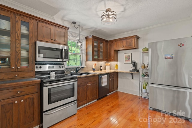 747 9th St NW, Hickory, NC 28601 - kitchen with stainless steel appliances, ornamental molding, backsplash, glass insert cabinets, and hanging light fixtures