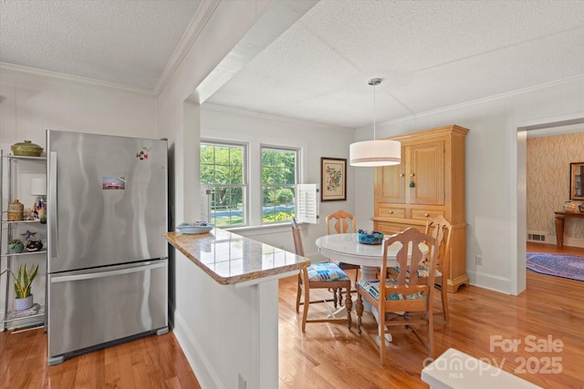747 9th St NW, Hickory, NC 28601 - kitchen featuring freestanding refrigerator, a textured ceiling, crown molding, light wood-type flooring, and a peninsula