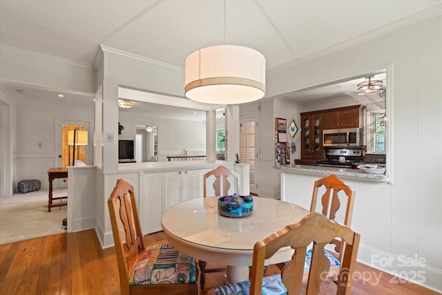747 9th St NW, Hickory, NC 28601 - dining space with crown molding, light wood-style flooring, a decorative wall, and a textured ceiling