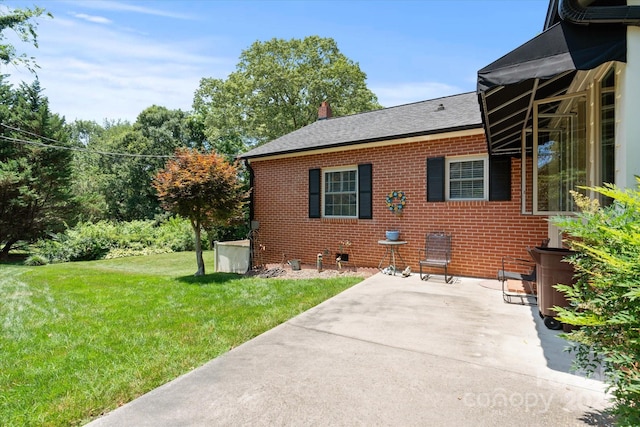 747 9th St NW, Hickory, NC 28601 - view of side of property with a patio, brick siding, a lawn, and a chimney