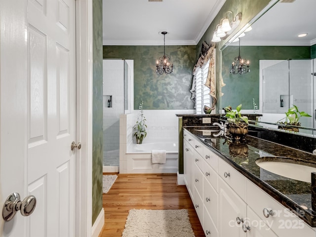 5572 Yorke St NW, Concord, NC 28027 - bathroom featuring a chandelier, double vanity, crown molding, a garden tub, and wood finished floors