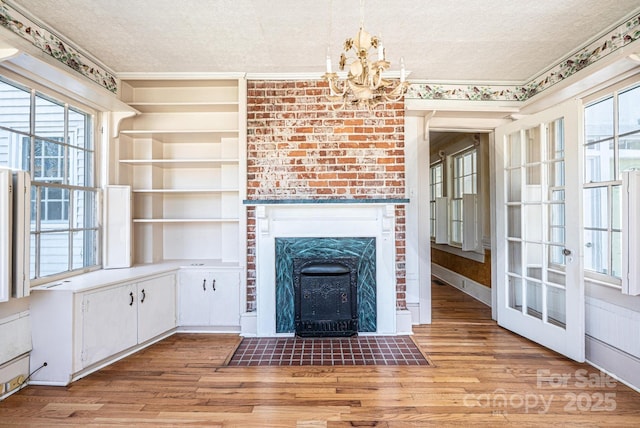 1010 College Ave SW, Lenoir, NC 28645 - unfurnished living room featuring light wood-type flooring, a chandelier, a fireplace with flush hearth, and a textured ceiling