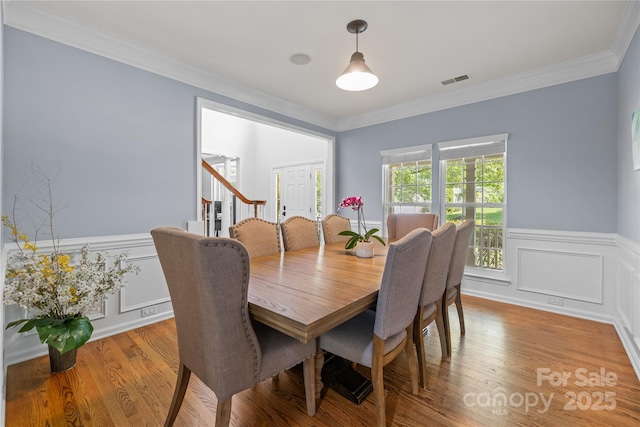 6800 Augustine Way, Charlotte, NC 28270 - dining space with stairway, a wainscoted wall, crown molding, light wood finished floors, and a decorative wall