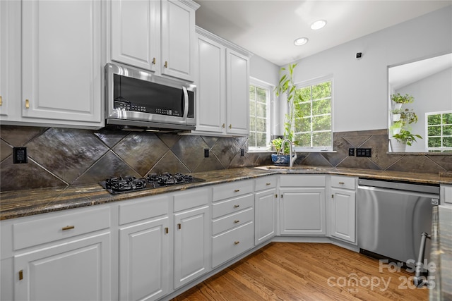 6800 Augustine Way, Charlotte, NC 28270 - kitchen featuring appliances with stainless steel finishes, white cabinets, light wood-style flooring, backsplash, and dark stone countertops