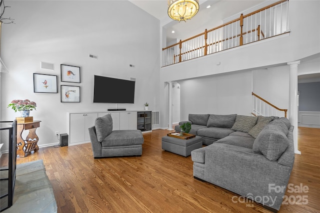 6800 Augustine Way, Charlotte, NC 28270 - living room featuring decorative columns, a towering ceiling, wood finished floors, a chandelier, and stairs