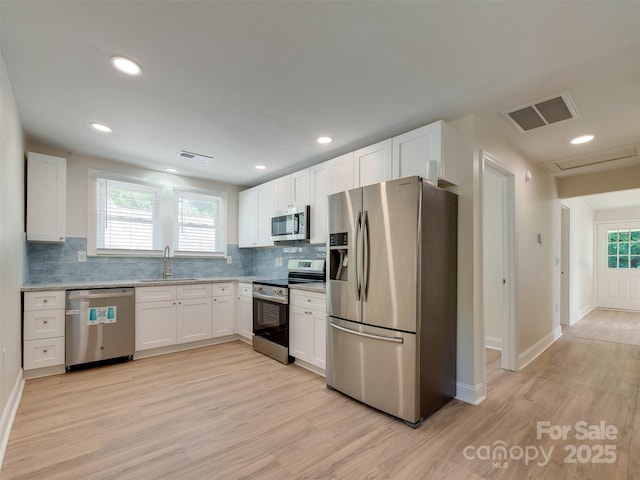 2414 Lane St, Kannapolis, NC 28083 - kitchen with stainless steel appliances, light wood-type flooring, white cabinets, decorative backsplash, and recessed lighting