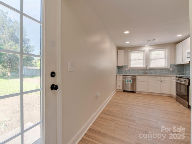 2414 Lane St, Kannapolis, NC 28083 - kitchen with appliances with stainless steel finishes, tasteful backsplash, white cabinetry, light wood-type flooring, and recessed lighting