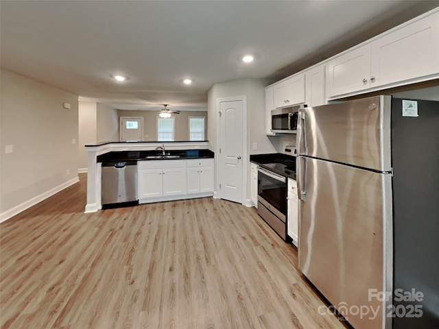 115 Dove Ave SW, Concord, NC 28025 - kitchen featuring appliances with stainless steel finishes, a peninsula, light wood-style flooring, white cabinets, and recessed lighting
