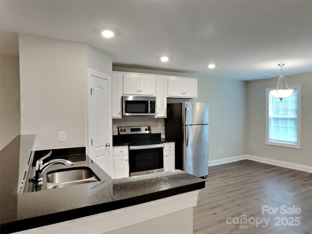 115 Dove Ave SW, Concord, NC 28025 - kitchen featuring appliances with stainless steel finishes, dark countertops, white cabinets, a peninsula, and recessed lighting