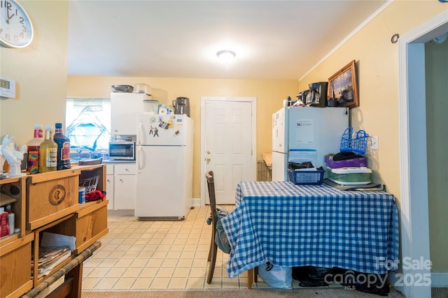 3037 Marlowe Ave, Charlotte, NC 28208 - kitchen with freestanding refrigerator, stainless steel microwave, white cabinetry, and light tile patterned flooring