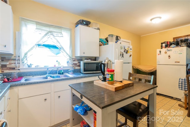 3037 Marlowe Ave, Charlotte, NC 28208 - kitchen with freestanding refrigerator, white cabinetry, stainless steel microwave, and dark countertops