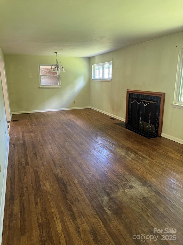 1239 8th St NE, Hickory, NC 28601 - unfurnished living room with wood finished floors, a tile fireplace, and a chandelier