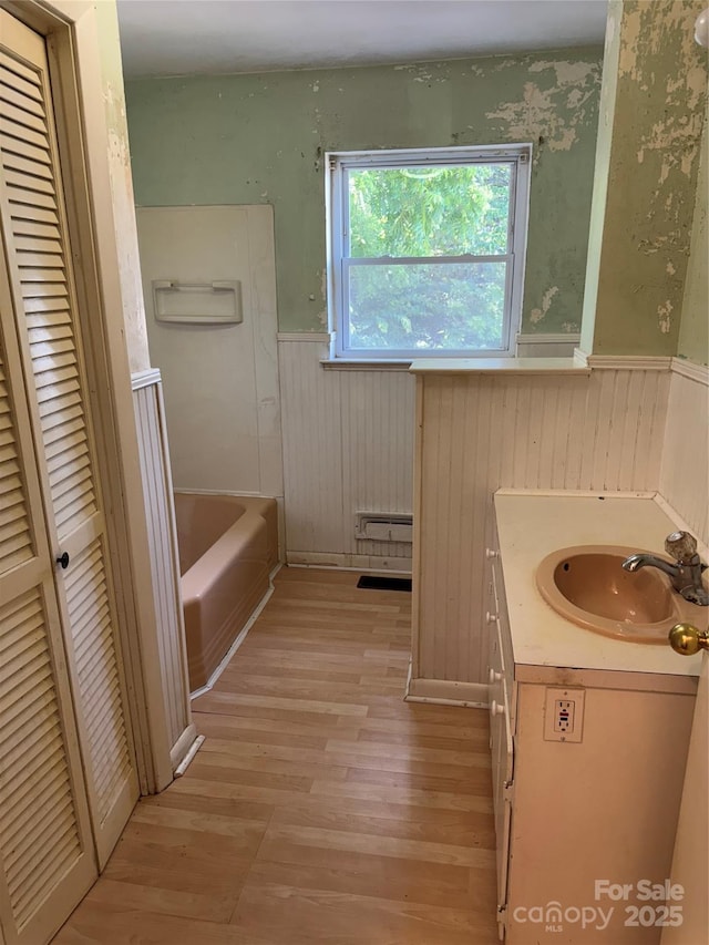 1239 8th St NE, Hickory, NC 28601 - full bathroom featuring a wainscoted wall, wood finished floors, a tub to relax in, vanity, and a closet