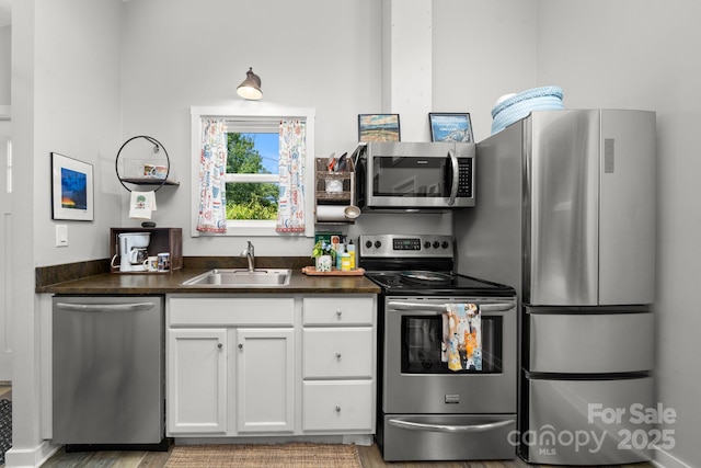 211 Summer St, Swannanoa, NC 28778 - kitchen with stainless steel appliances, dark countertops, white cabinetry, and light wood-style flooring