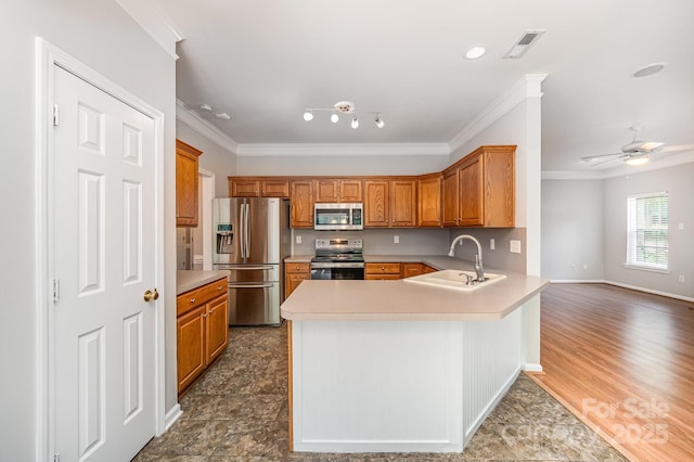 7731 Sedgebrook Dr E, Stanley, NC 28164 - kitchen featuring stainless steel appliances, ornamental molding, a peninsula, light countertops, and brown cabinetry