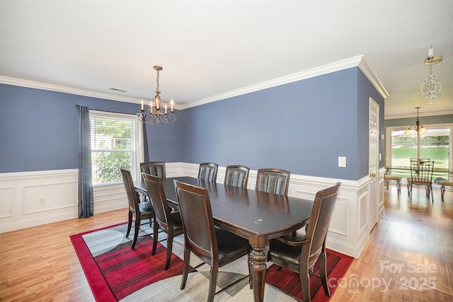 4732 Meadowfield Rd Unit L35, Charlotte, NC 28215 - dining space featuring a chandelier, ornamental molding, light wood finished floors, wainscoting, and a decorative wall