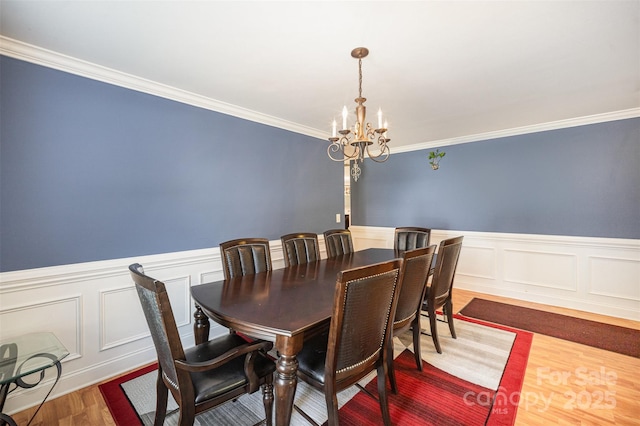 4732 Meadowfield Rd Unit L35, Charlotte, NC 28215 - dining room with a chandelier, wood finished floors, crown molding, a wainscoted wall, and a decorative wall