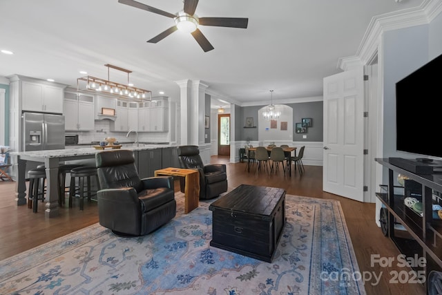 313 Sunset View Ct, York, SC 29745 - living room with dark wood finished floors, a ceiling fan, a chandelier, crown molding, and a wainscoted wall