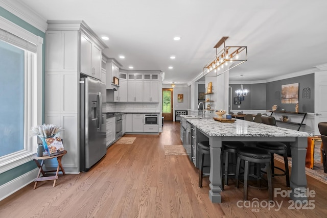 313 Sunset View Ct, York, SC 29745 - kitchen featuring appliances with stainless steel finishes, ornamental molding, a chandelier, light stone counters, and light wood-style flooring