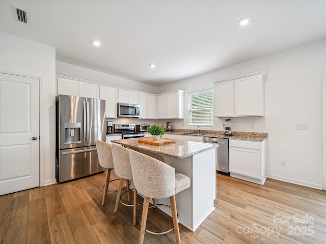 3077 Light Ridge Ct SW, Concord, NC 28027 - kitchen featuring appliances with stainless steel finishes, light wood-type flooring, white cabinetry, a center island, and recessed lighting