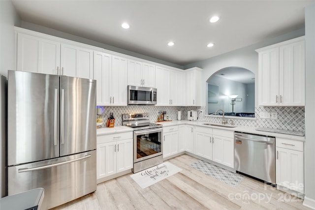 713 Torrey Pines Ln, Fort Mill, SC 29715 - kitchen with stainless steel appliances, arched walkways, light wood finished floors, light countertops, and backsplash