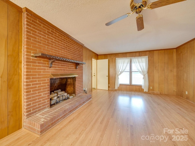 3113 Old Pageland Marshville Rd, Wingate, NC 28174 - unfurnished living room with a ceiling fan, wood finished floors, wood walls, a textured ceiling, and a brick fireplace