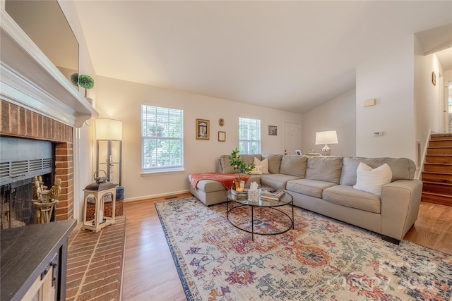 6418 Tivoli Ct, Charlotte, NC 28211 - living room featuring vaulted ceiling, wood finished floors, a brick fireplace, and stairs