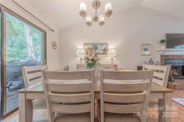 6418 Tivoli Ct, Charlotte, NC 28211 - dining space with vaulted ceiling, a chandelier, wood finished floors, and a brick fireplace
