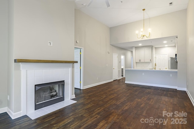 795 Peninsula Dr, Davidson, NC 28036 - unfurnished living room with high vaulted ceiling, dark wood-style floors, a chandelier, and a tile fireplace