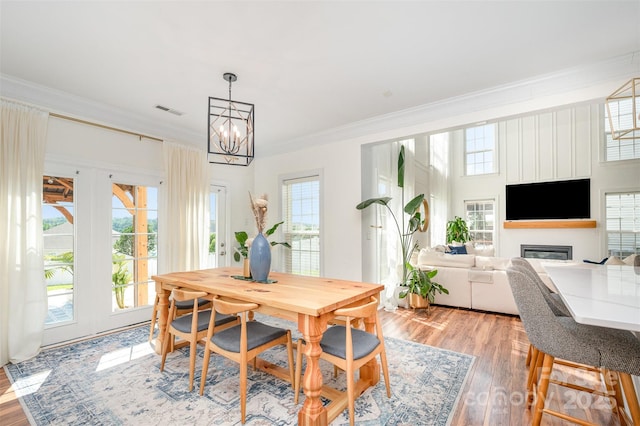 2380 Fairport Dr SE, Concord, NC 28025 - dining space featuring a chandelier, ornamental molding, light wood-style flooring, and a glass covered fireplace