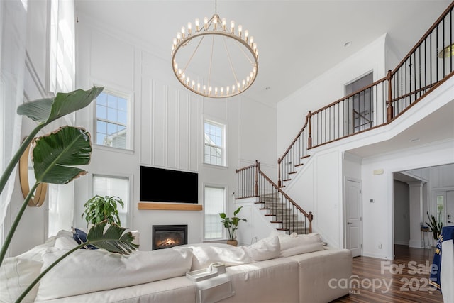 2380 Fairport Dr SE, Concord, NC 28025 - living room featuring a towering ceiling, stairway, wood finished floors, a chandelier, and a glass covered fireplace