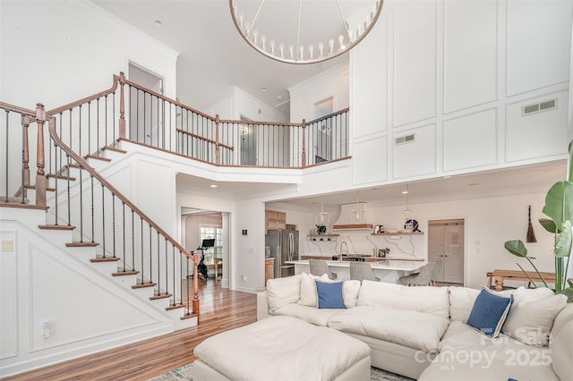 2380 Fairport Dr SE, Concord, NC 28025 - living room featuring a high ceiling, light wood-style flooring, ornamental molding, and stairs