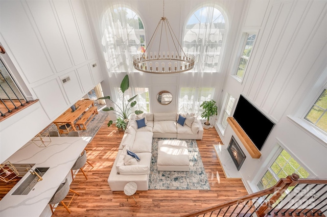 2380 Fairport Dr SE, Concord, NC 28025 - living room featuring a towering ceiling, wood finished floors, a chandelier, and a fireplace with flush hearth