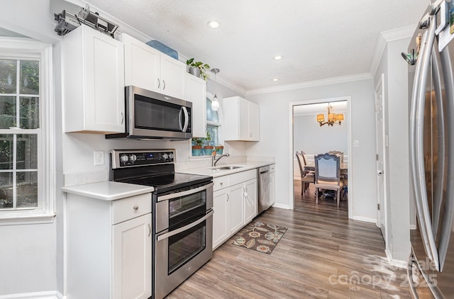 80 Lecline Cir NE, Concord, NC 28025 - kitchen with appliances with stainless steel finishes, light countertops, light wood-type flooring, ornamental molding, and a chandelier