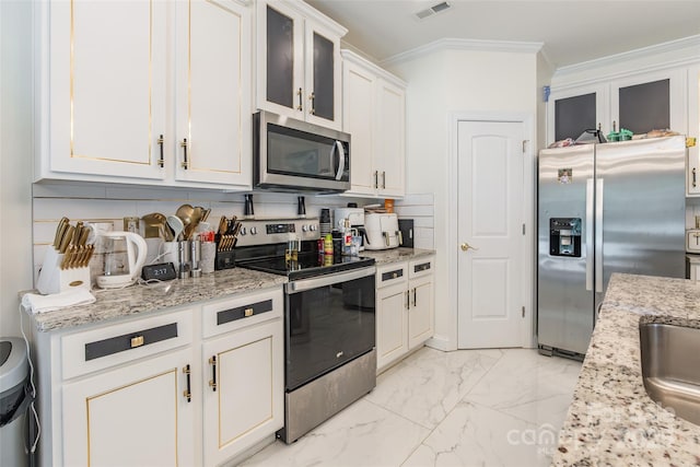 154 Tanner Loop, Troutman, NC 28166 - kitchen with appliances with stainless steel finishes, ornamental molding, glass insert cabinets, white cabinets, and light stone counters