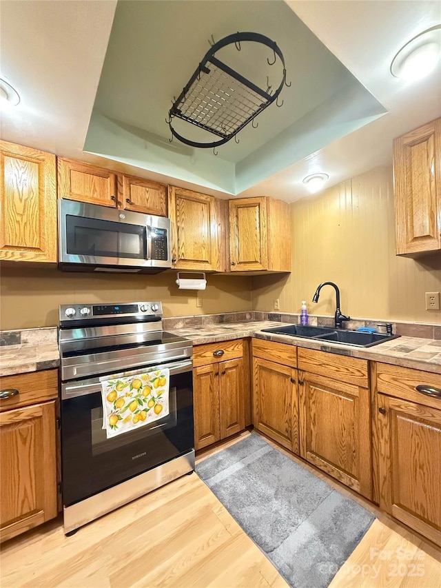 5685 Pine Ridge Dr, Connelly Springs, NC 28612 - kitchen featuring stainless steel appliances, a tray ceiling, light wood-style floors, and brown cabinetry