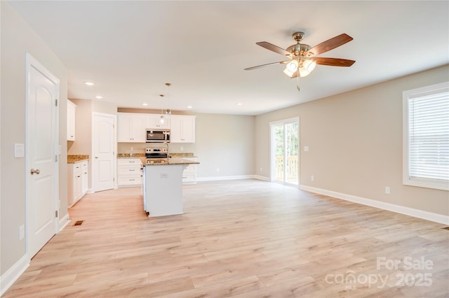 206 N Kayla Dr, Salisbury, NC 28146 - kitchen featuring stainless steel microwave, electric range oven, open floor plan, ceiling fan, and an island with sink