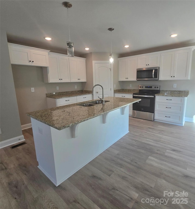 200 N Kayla Dr, Salisbury, NC 28146 - kitchen with stainless steel appliances, white cabinets, a kitchen island with sink, light stone countertops, and light wood-style flooring