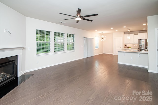 17718 Terryglass Ln, Charlotte, NC 28278 - unfurnished living room with a chandelier, ceiling fan, recessed lighting, dark wood finished floors, and a glass covered fireplace