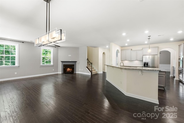 2525 Surveyor General Dr, Waxhaw, NC 28173 - kitchen with stainless steel appliances, arched walkways, a lit fireplace, a breakfast bar, and dark wood-style floors
