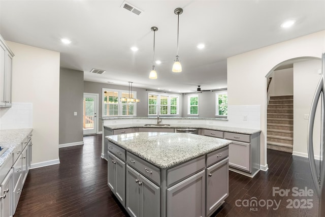 2525 Surveyor General Dr, Waxhaw, NC 28173 - kitchen with gray cabinets, a peninsula, backsplash, dark wood-type flooring, and a kitchen island
