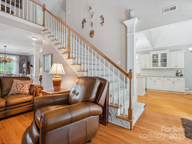 13101 Kensworth Ct, Charlotte, NC 28277 - living area featuring light wood finished floors, stairs, ornate columns, a chandelier, and a high ceiling