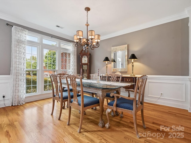 13101 Kensworth Ct, Charlotte, NC 28277 - dining area featuring a chandelier, ornamental molding, light wood-style floors, a wainscoted wall, and a decorative wall