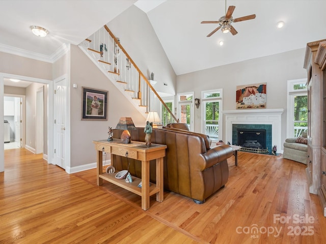 13101 Kensworth Ct, Charlotte, NC 28277 - living room with stairs, a ceiling fan, light wood-style floors, a tile fireplace, and high vaulted ceiling