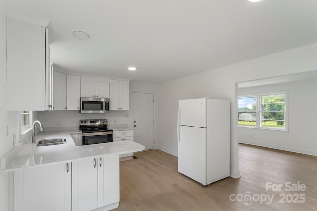4146 Old State Rd, Newton, NC 28658 - kitchen featuring appliances with stainless steel finishes, light countertops, light wood-style floors, white cabinetry, and ornamental molding