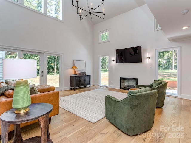 202 Walden Ln, Weddington, NC 28104 - living room featuring a high ceiling, a glass covered fireplace, light wood finished floors, plenty of natural light, and a chandelier